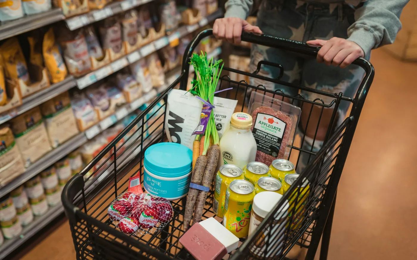 a person pushing a shopping cart full of food by Karsten Winegeart courtesy of Unsplash.