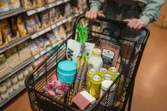 a person pushing a shopping cart full of food by Karsten Winegeart courtesy of Unsplash.