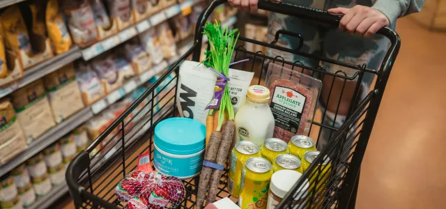 a person pushing a shopping cart full of food by Karsten Winegeart courtesy of Unsplash.